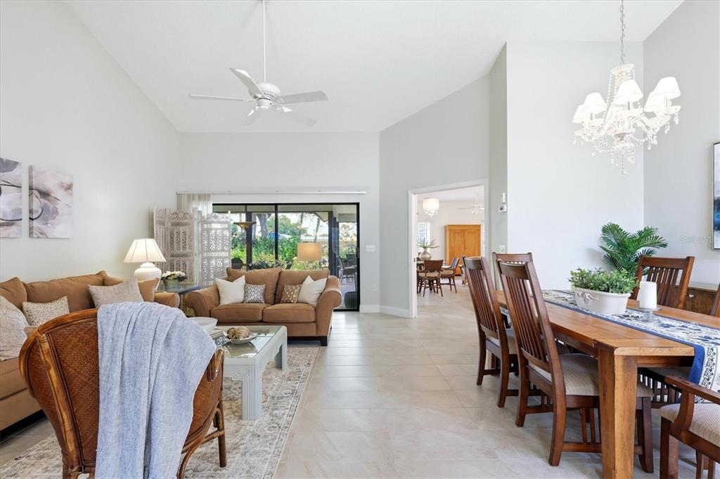 A living and dining area with tile floors, vaulted ceilings, and a sliding glass door — 216 CARRIAGE HOUSE LANE UNIT 216, NOKOMIS, FL