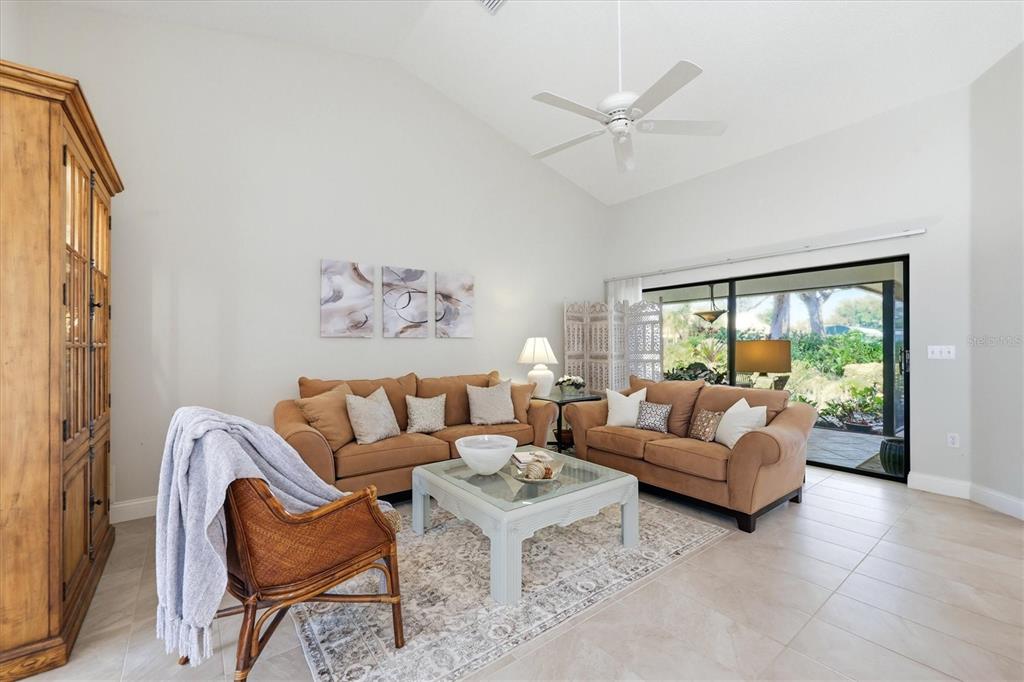 A living room features two tan sofas, a glass coffee table, and a wicker chair — 216 CARRIAGE HOUSE LANE UNIT 216, NOKOMIS, FL