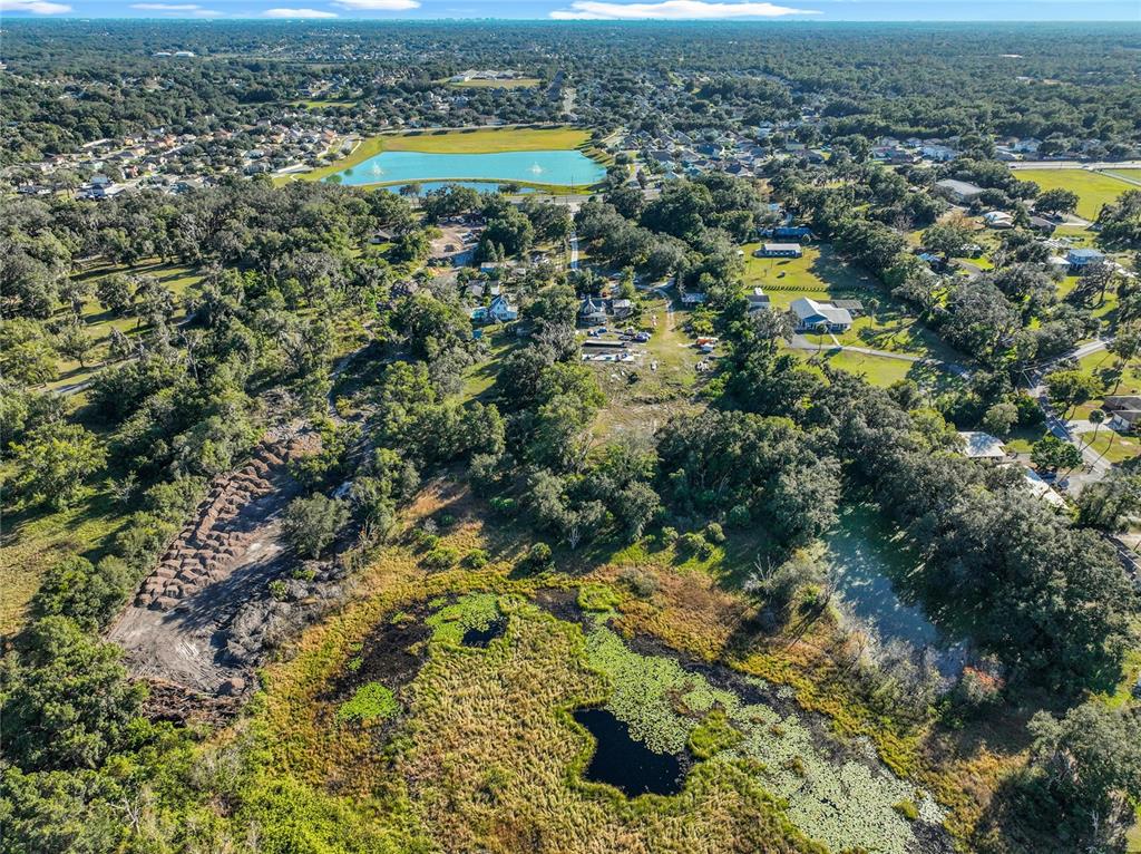 An aerial view shows a large pond in the foreground and a residential neighborhood beyond — 7717 CLARCONA OCOEE ROAD Lot 2, ORLANDO, FL