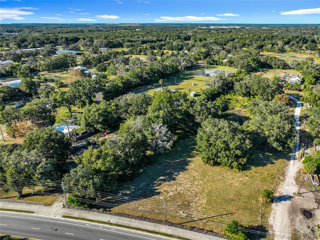 An aerial view shows a vacant, tree-lined lot situated next to a road — 7717 CLARCONA OCOEE ROAD Lot 2, ORLANDO, FL