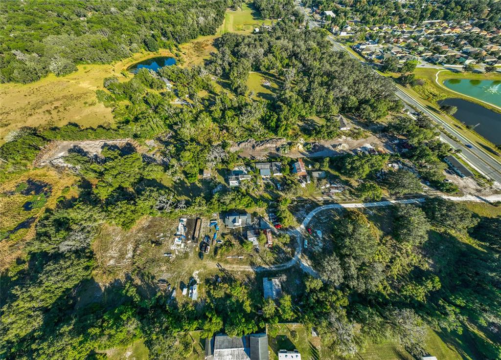 An aerial view shows a rural property with several small buildings, trees, and dirt paths — 7717 CLARCONA OCOEE ROAD Lot 2, ORLANDO, FL