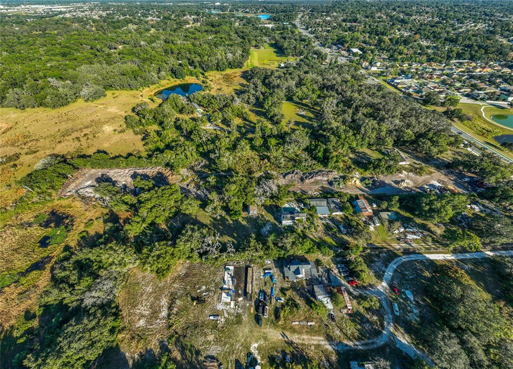 An aerial view shows a rural property with several buildings, wooded areas, and a small pond — 7717 CLARCONA OCOEE ROAD Lot 2, ORLANDO, FL
