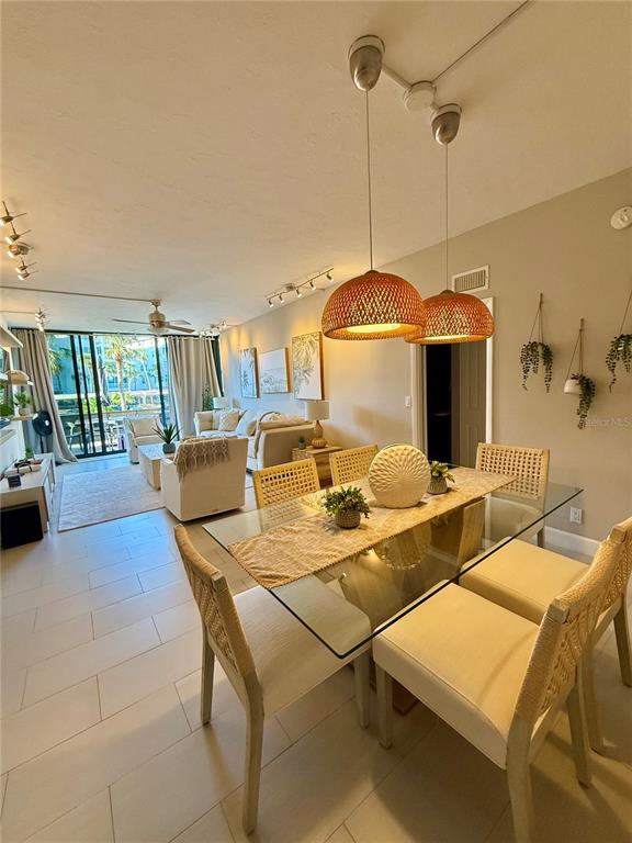 A dining area with a glass table and wicker chairs sits adjacent to a living room — 5855 MIDNIGHT PASS ROAD UNIT 108, SARASOTA, FL