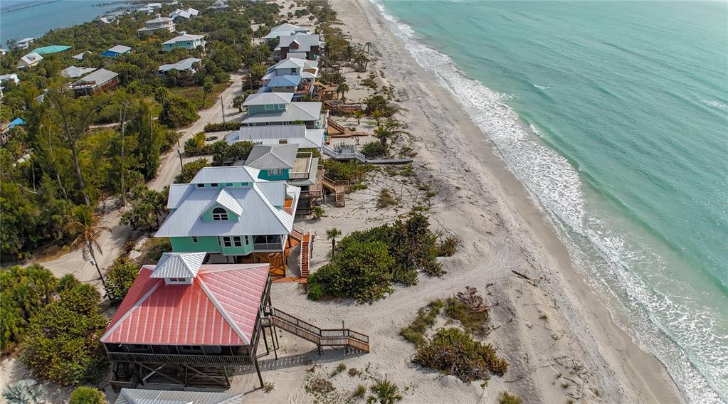 An aerial view of several elevated beach houses situated along a sandy coastline — 8796 GRAND AVENUE, PLACIDA, FL