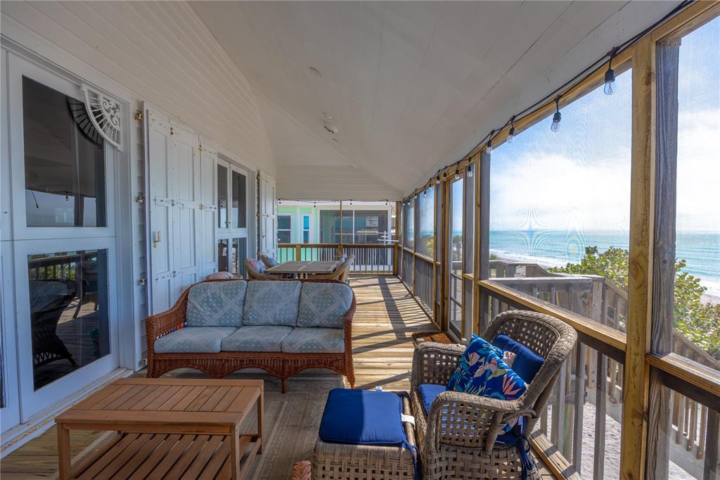 A screened-in wooden porch features wicker furniture and a direct view of the ocean — 8796 GRAND AVENUE, PLACIDA, FL