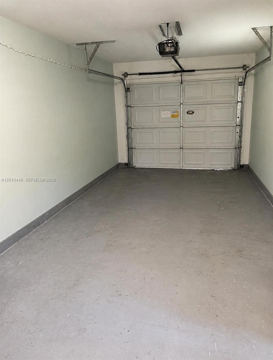 A single-car garage features light green walls, a gray concrete floor, and a sectional door — 1601 N K St, Lake Worth FL 33460, LAKE WORTH, FL