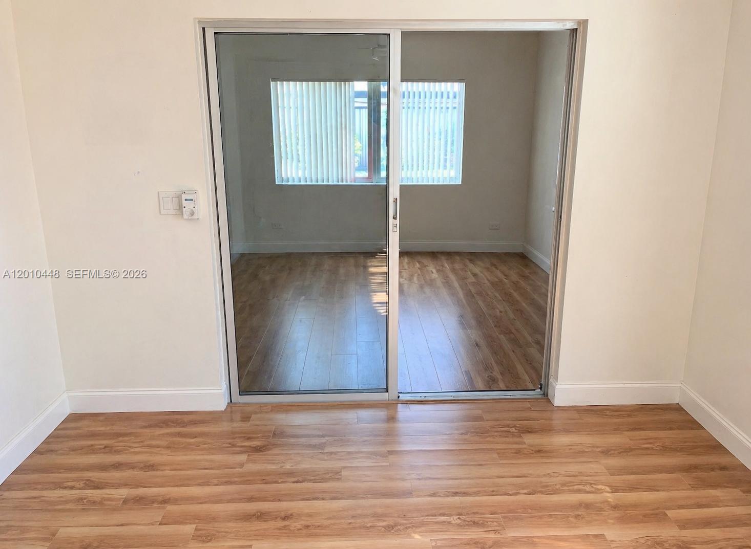 A room with wood-look flooring features a sliding glass door leading to another room — 1601 N K St, Lake Worth FL 33460, LAKE WORTH, FL