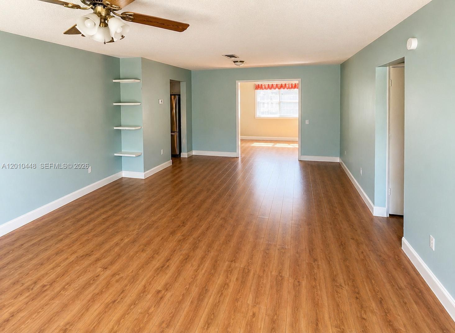 An empty living room features light blue walls, wood-look flooring, and built-in wall shelves — 1601 N K St, Lake Worth FL 33460, LAKE WORTH, FL