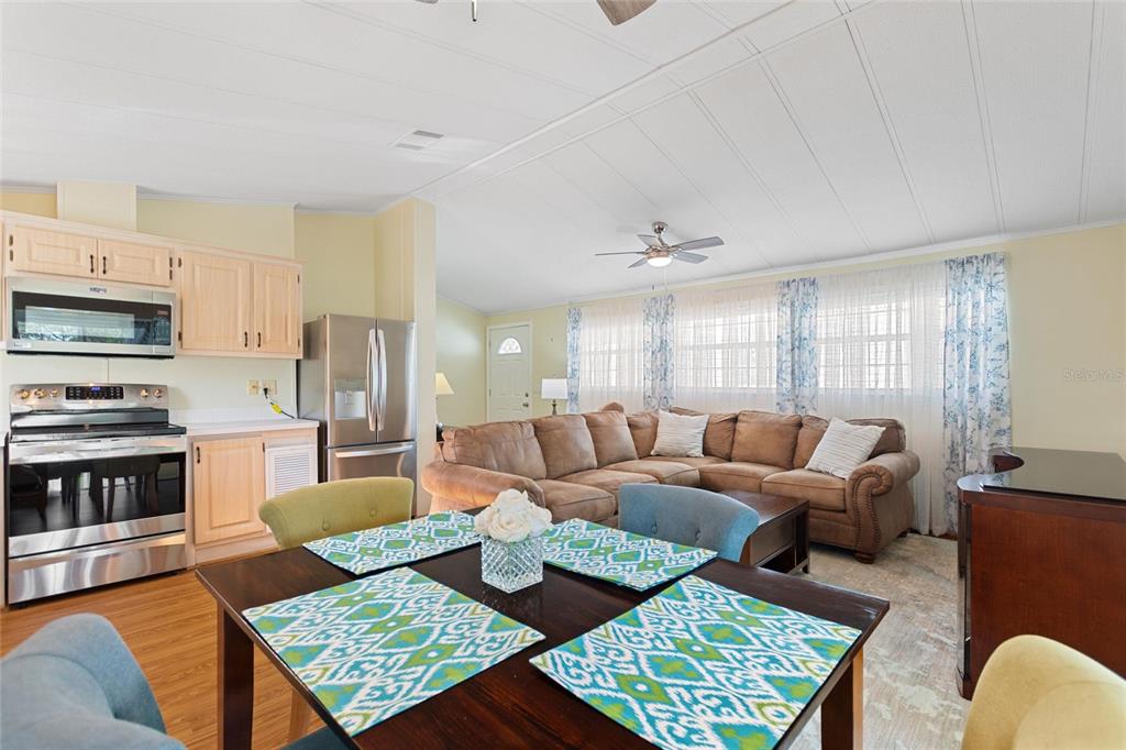 An open-concept living and dining area features a kitchen, sectional sofa, and dining table — 16 CHAMPIONSHIP DR, DAVENPORT, FL