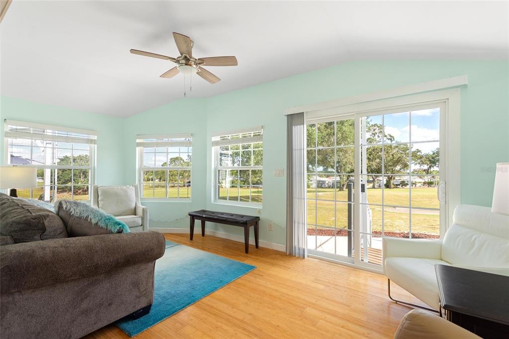 A living room with light green walls, hardwood floors, a ceiling fan, and sliding doors — 16 CHAMPIONSHIP DR, DAVENPORT, FL