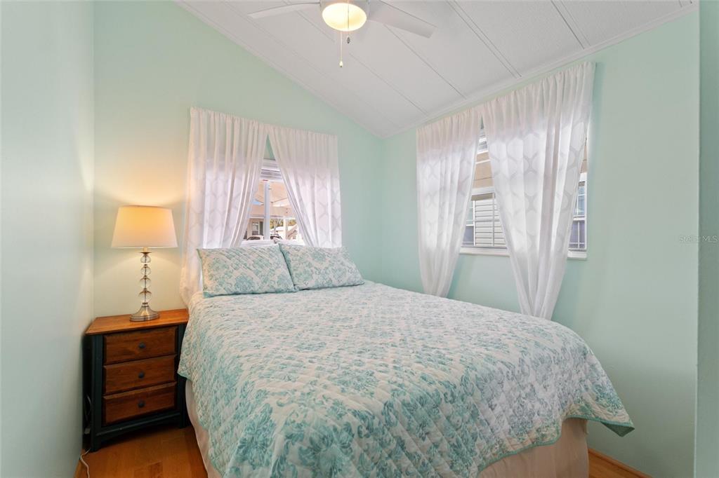 A bedroom with light green walls, a bed with patterned bedding, and two windows — 16 CHAMPIONSHIP DR, DAVENPORT, FL