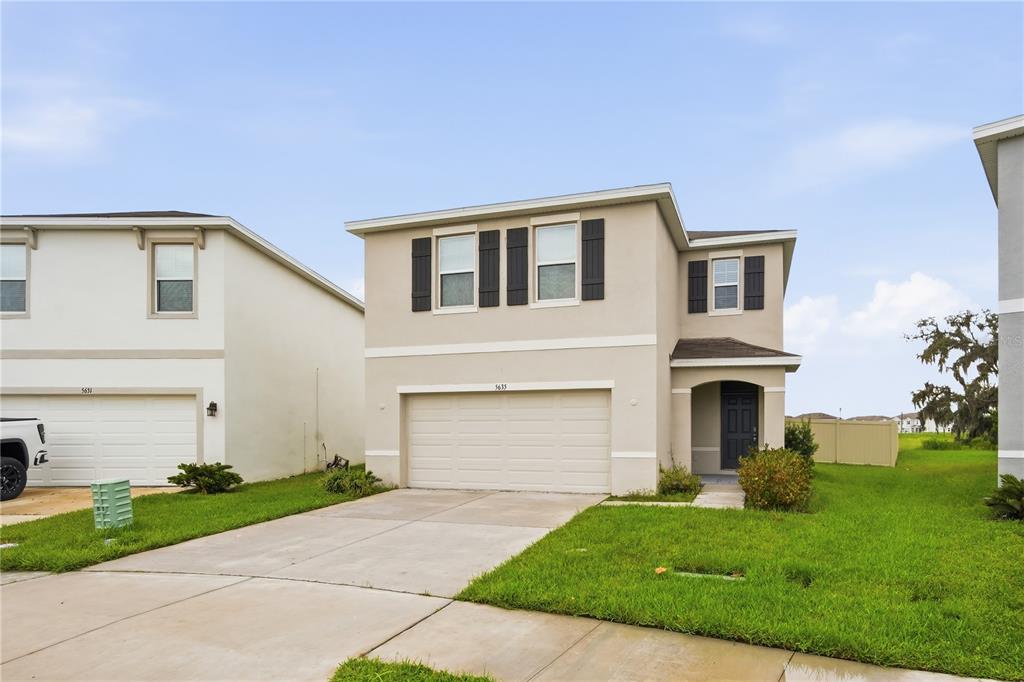 A two-story beige house with a two-car garage and a front entrance under a portico — 5635 HOLLINGWORTH TRAIL, WESLEY CHAPEL, FL