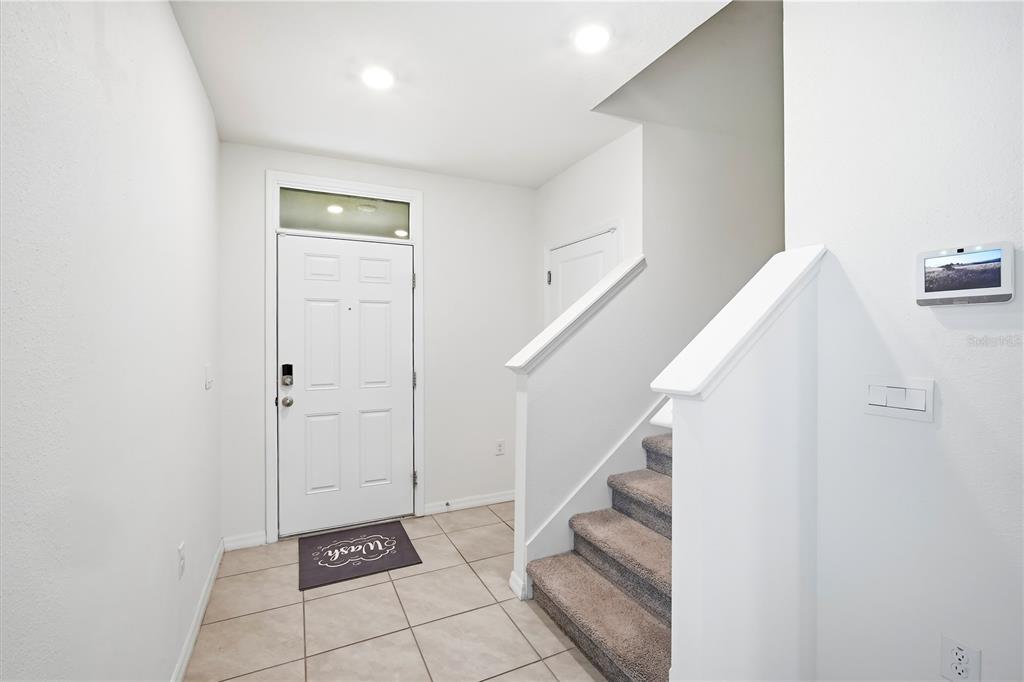 A bright entryway features a white front door, tiled flooring, and carpeted stairs — 5635 HOLLINGWORTH TRAIL, WESLEY CHAPEL, FL