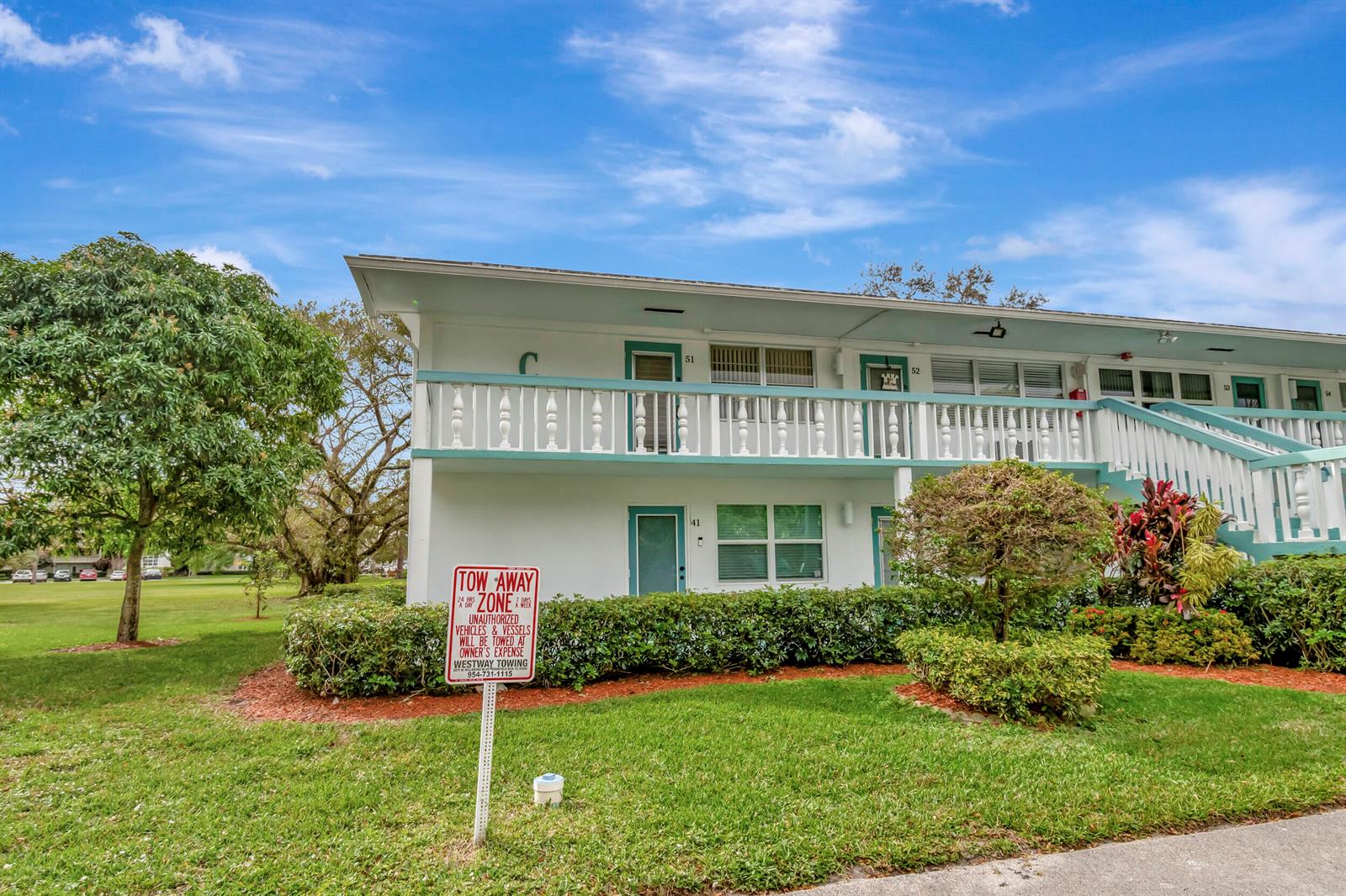 A two-story apartment building exterior features white walls, teal trim, and a balcony with railings — 51 Ventnor C, Deerfield Beach FL 33442, DEERFIELD BEACH, FL