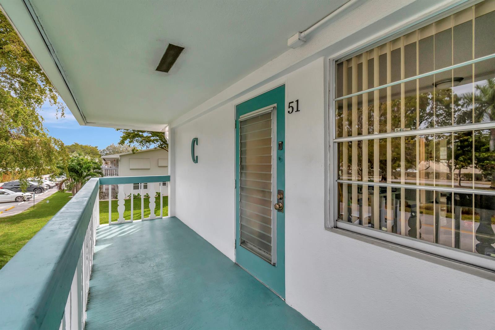 An exterior balcony features a teal door labeled 51, a matching floor, and a white railing — 51 Ventnor C, Deerfield Beach FL 33442, DEERFIELD BEACH, FL