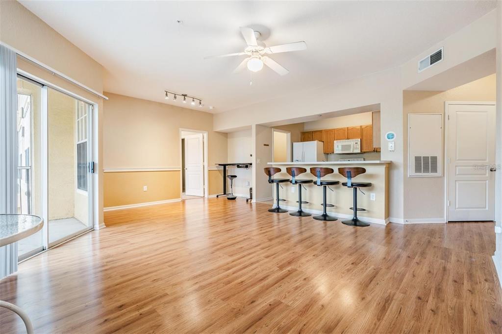 An open-concept living and dining area features wood-look flooring, a breakfast bar, and sliding doors — 5125 PALM SPRINGS BOULEVARD UNIT 8203, TAMPA, FL