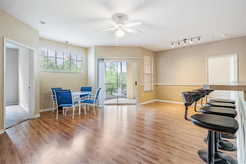 A living and dining area with wood-look flooring, a ceiling fan, and a balcony entrance — 5125 PALM SPRINGS BOULEVARD UNIT 8203, TAMPA, FL