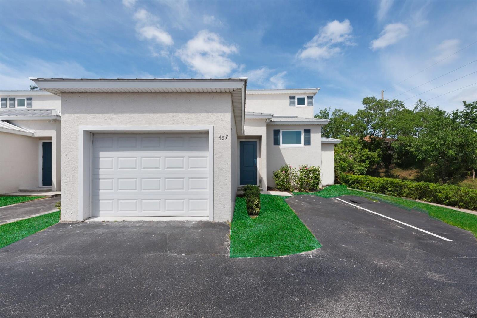 A two-story townhouse exterior features a white stucco facade, a garage, and a blue door — VERO BEACH, FL