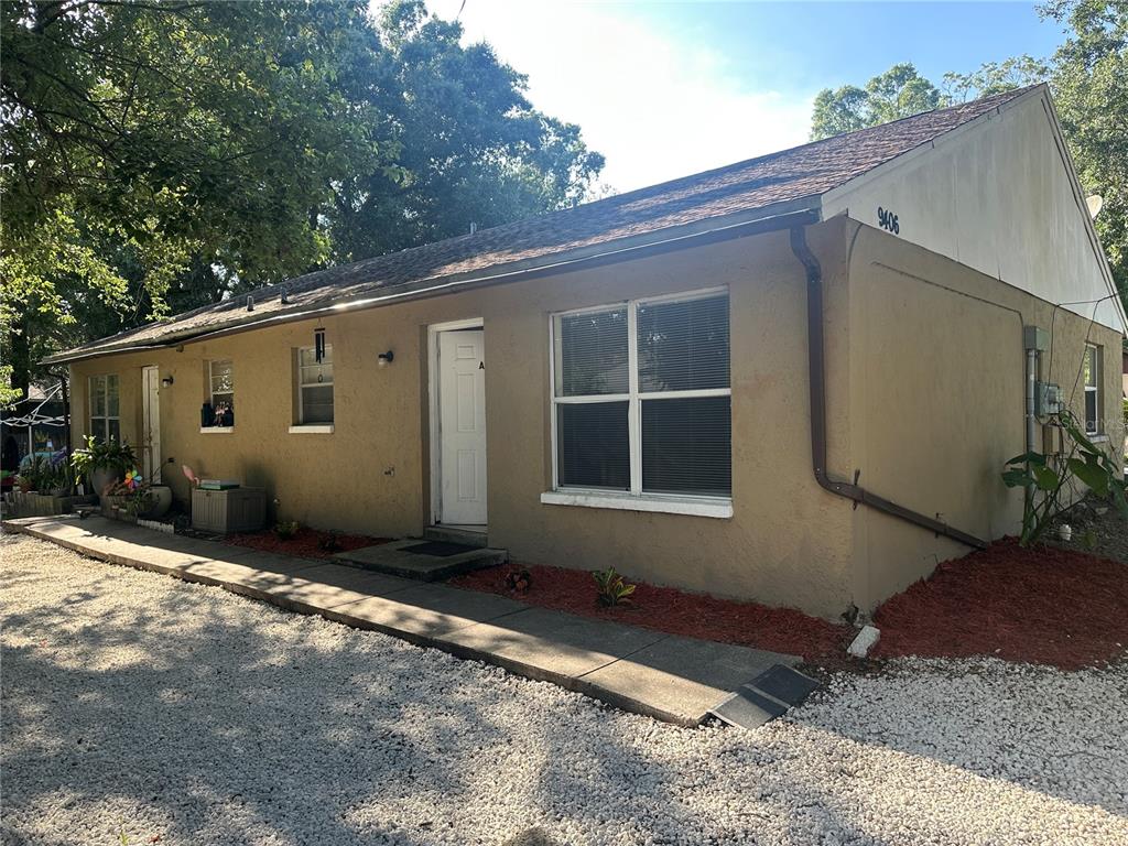 A single-story tan stucco building with a gravel driveway and a concrete walkway — 9406 N HARTTS DRIVE, TAMPA, FL