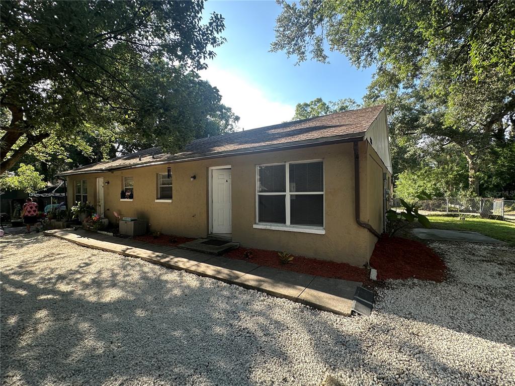 A tan house with a white gable roof sits behind a cracked concrete driveway — 9406 N HARTTS DRIVE, TAMPA, FL