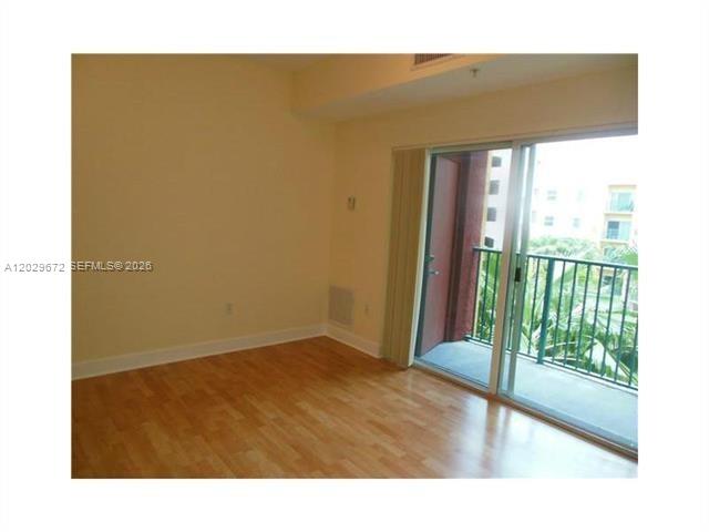 An empty room with light-colored walls, wood-look flooring, and a sliding glass door to a balcony — 6001 SW 70th St # 538, South Miami FL 33143, SOUTH MIAMI, FL