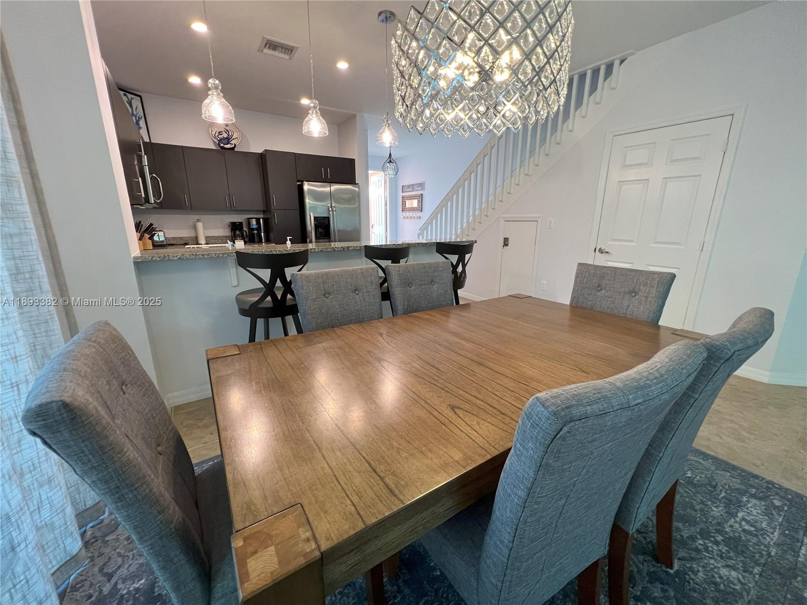 A dining area with a wooden table and gray chairs sits before a kitchen counter — 2361 SE 5th St, Pompano Beach FL 33062, POMPANO BEACH, FL