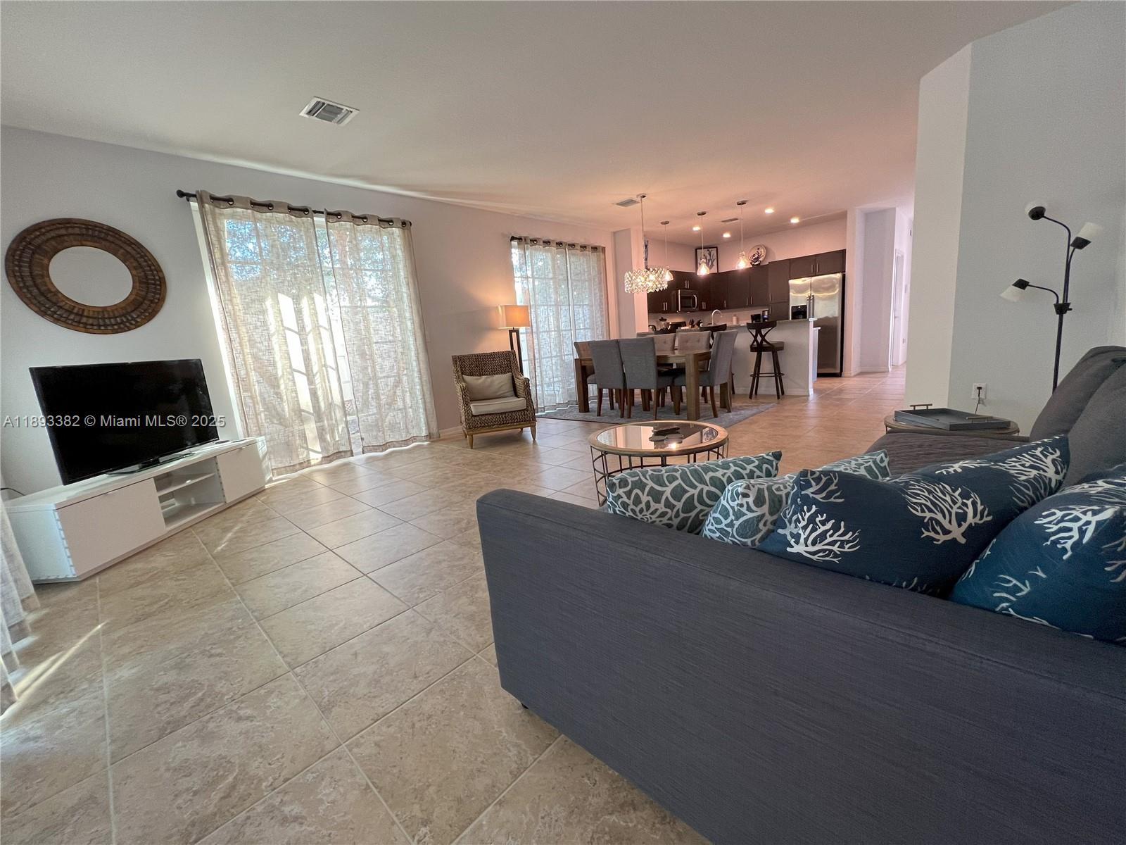 An open-concept living and dining area features tile flooring, a kitchen, and sliding glass doors — 2361 SE 5th St, Pompano Beach FL 33062, POMPANO BEACH, FL