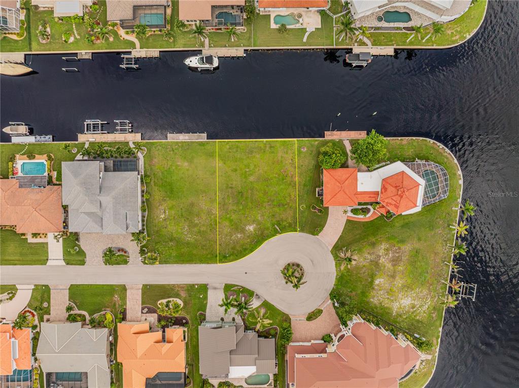 An aerial view shows a vacant waterfront lot situated between two existing residential properties — 5 TROPICANA DRIVE, PUNTA GORDA, FL