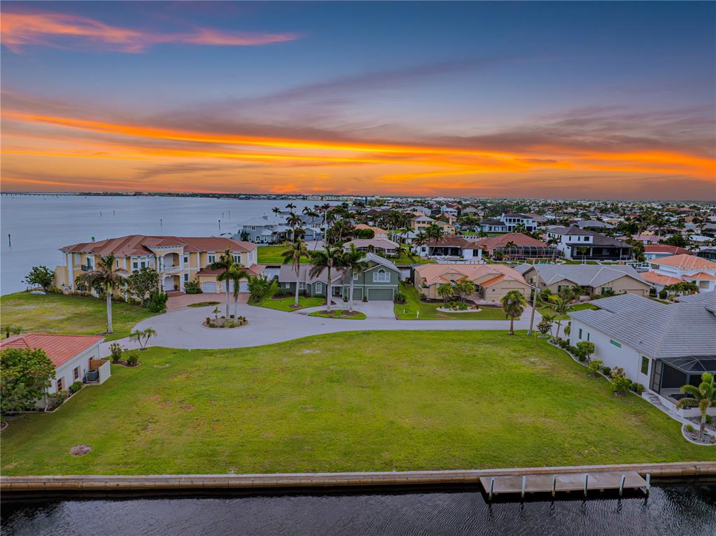 An aerial view of a vacant waterfront lot in a residential neighborhood at sunset — 5 TROPICANA DRIVE, PUNTA GORDA, FL
