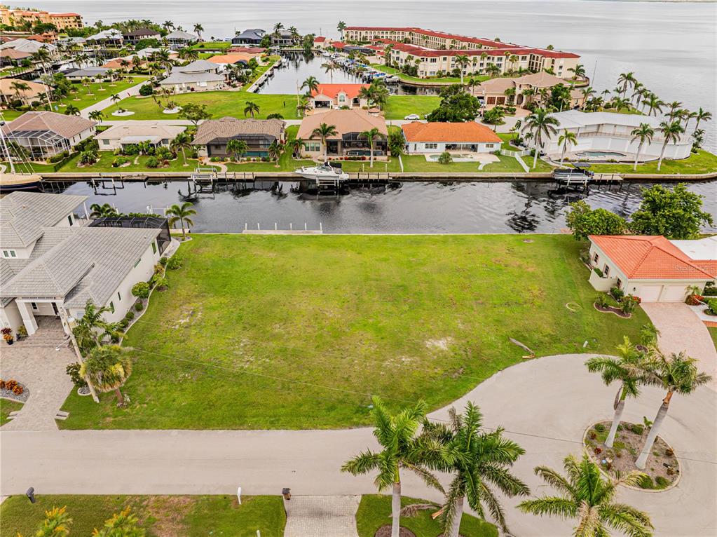 An aerial view shows a vacant waterfront residential lot situated between two existing houses — 5 TROPICANA DRIVE, PUNTA GORDA, FL