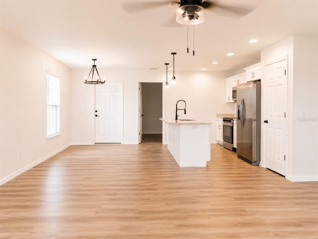 An open-concept kitchen and dining area features white cabinetry, a center island, and wood-look flooring — 318 EUCALYPTUS ROAD, LAKE WALES, FL