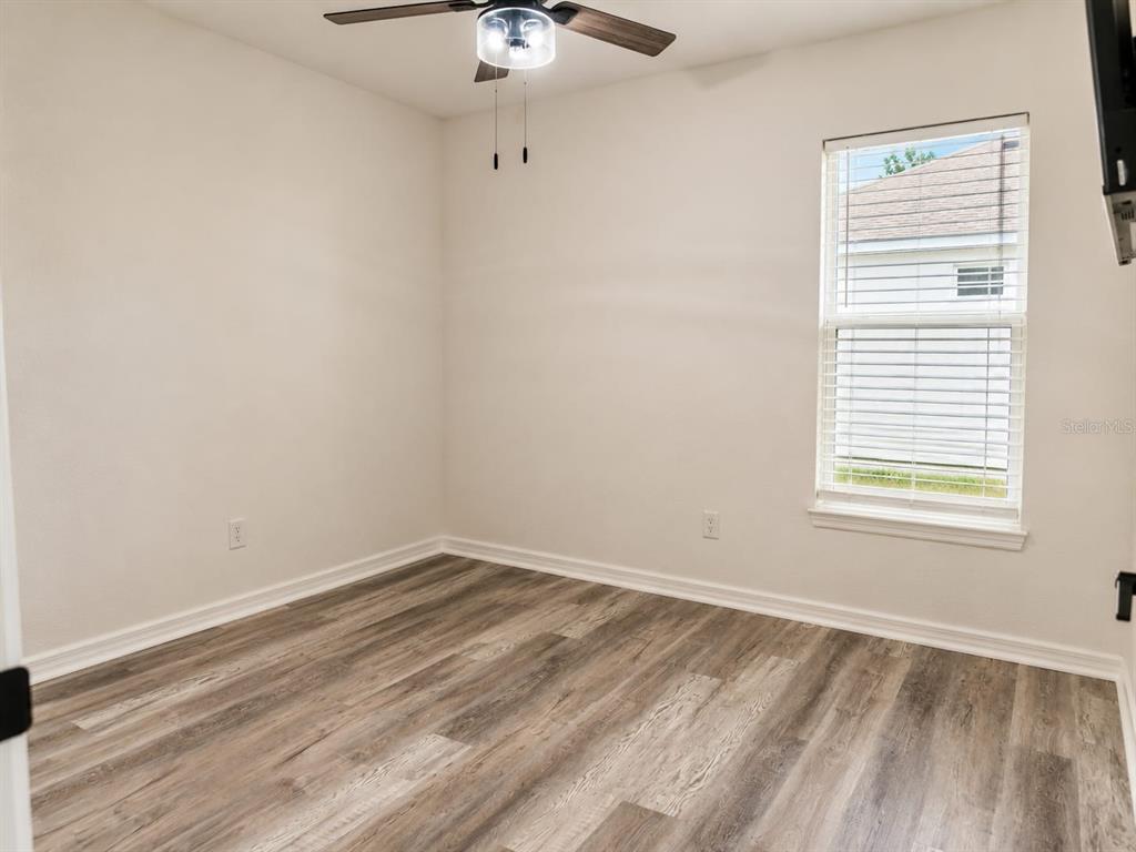 An empty room with light-colored walls, wood-look flooring, a ceiling fan, and a single window — 318 EUCALYPTUS ROAD, LAKE WALES, FL