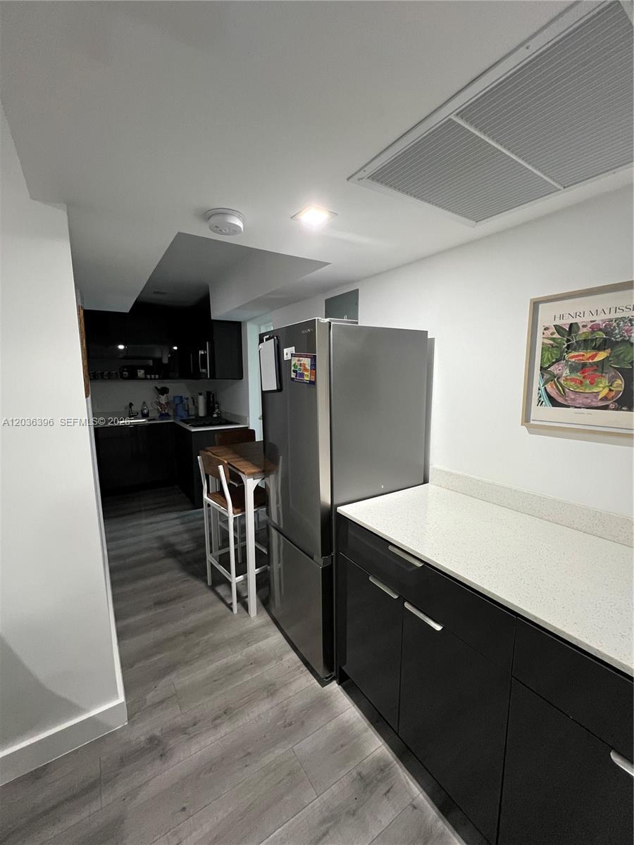 A kitchen features dark cabinets, a stainless steel refrigerator, and a small dining table — 2847 Polk St # 2, Hollywood FL 33020, HOLLYWOOD, FL