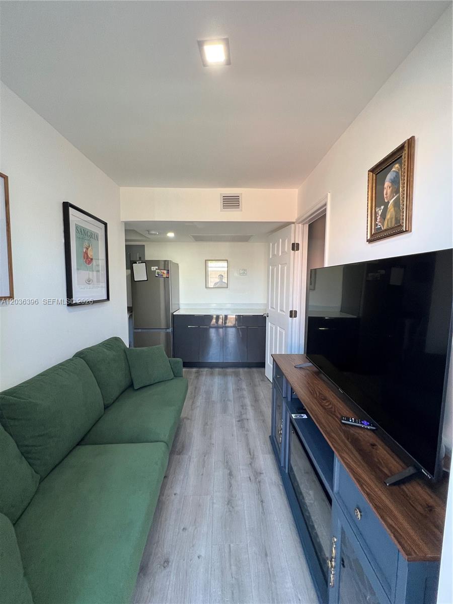 A living room features a green sofa, a television on a console, and a kitchen — 2847 Polk St # 2, Hollywood FL 33020, HOLLYWOOD, FL