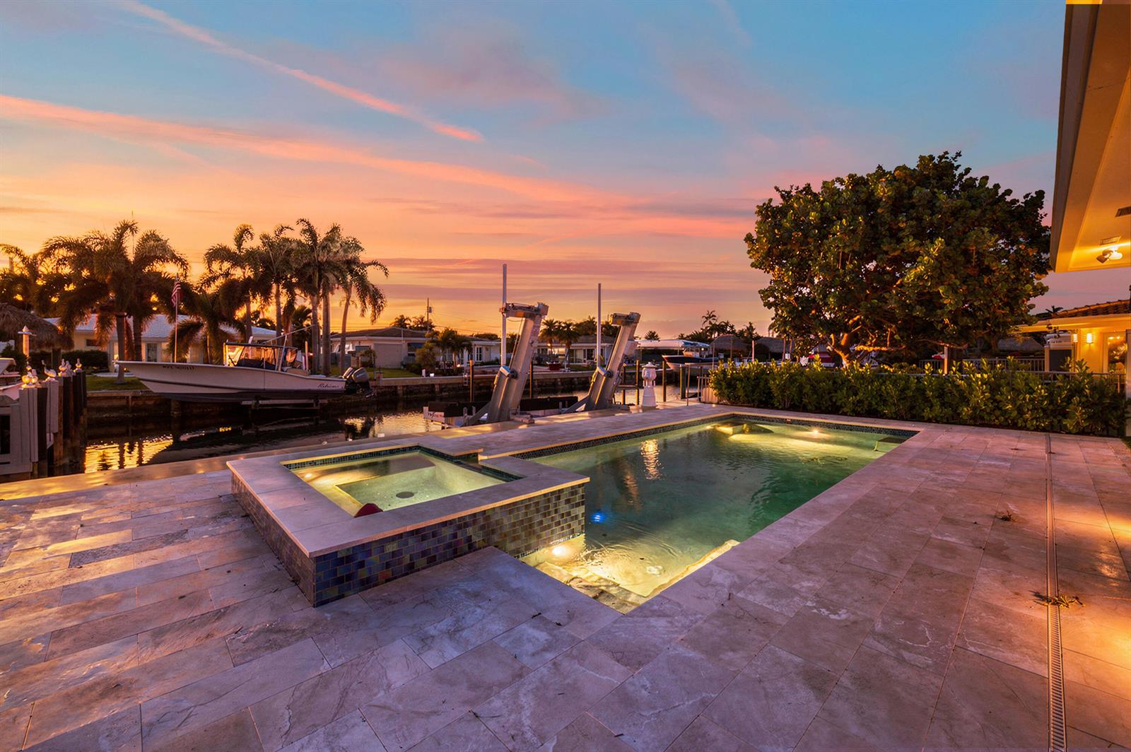A backyard pool and spa with stone decking overlook a canal at sunset — 511 SE 9th Avenue, Pompano Beach FL 33060, POMPANO BEACH, FL