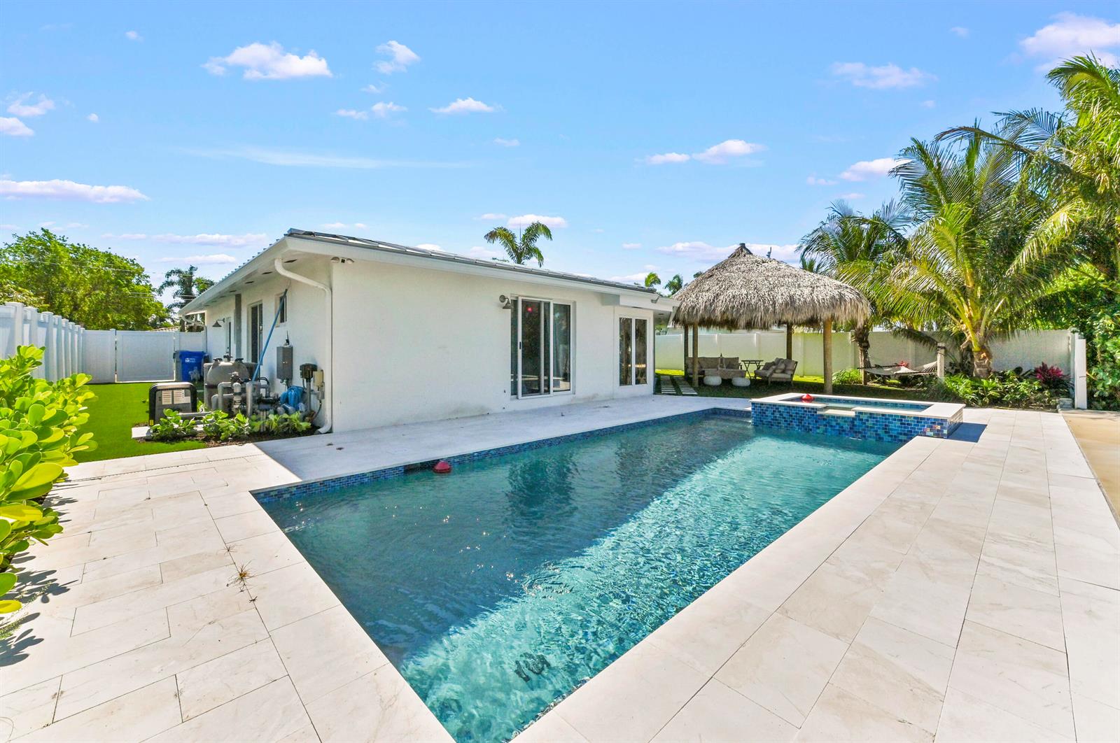 A backyard features a rectangular swimming pool with a tiled spa and a thatched gazebo — 511 SE 9th Avenue, Pompano Beach FL 33060, POMPANO BEACH, FL