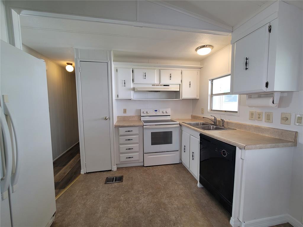 A kitchen features white cabinets, a white stove, a black dishwasher, and laminate countertops — 7209 EL MEYERS STREET, ZEPHYRHILLS, FL