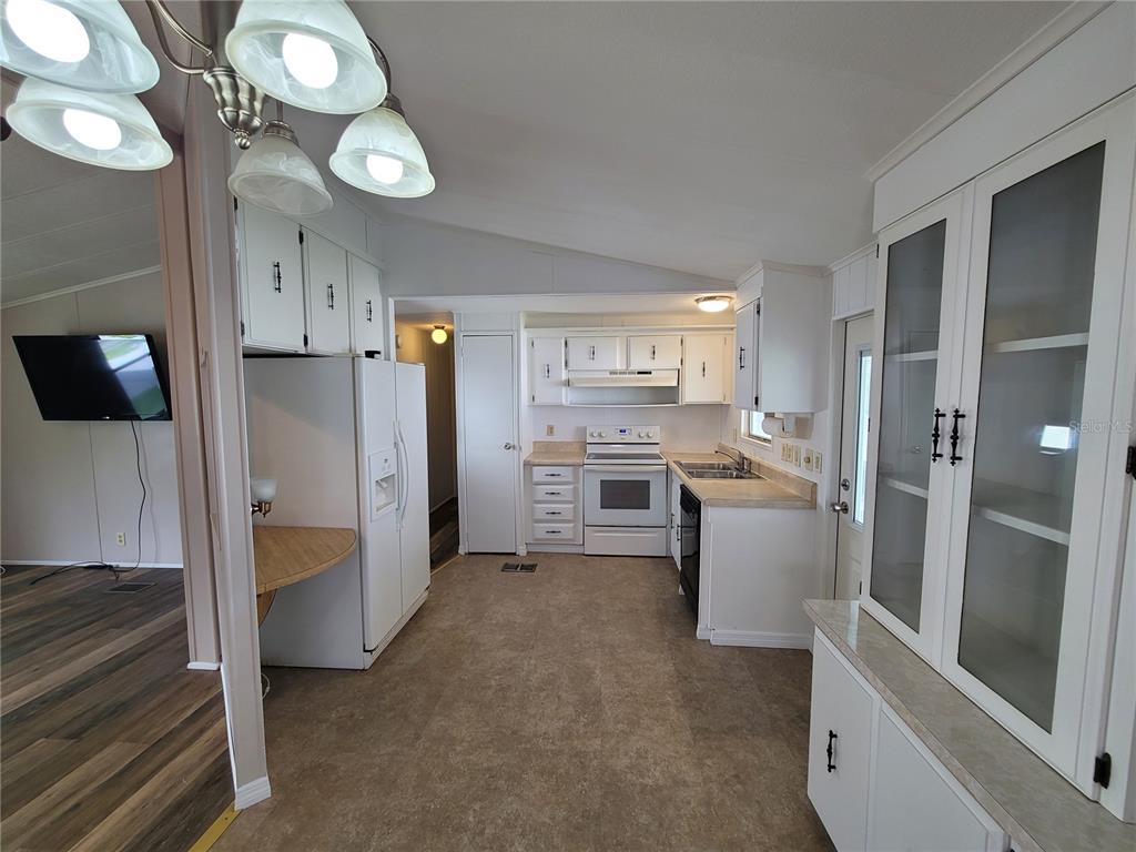 A kitchen with white cabinets, white appliances, and a glass-front display cabinet — 7209 EL MEYERS STREET, ZEPHYRHILLS, FL