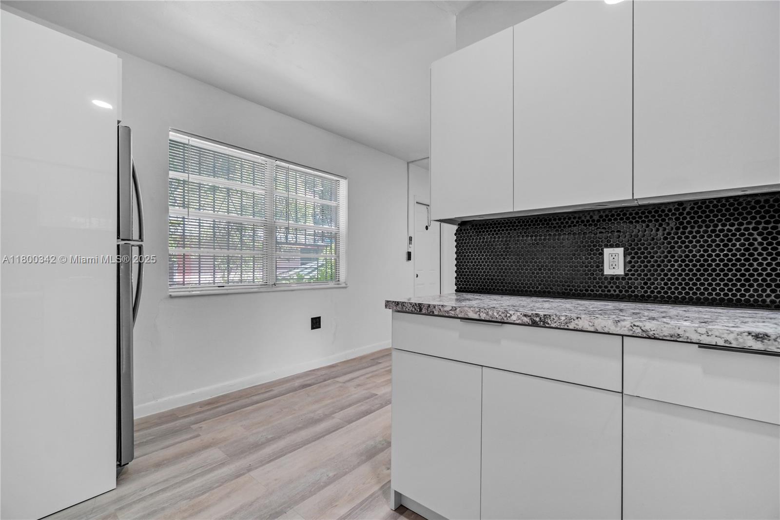 A kitchen features white cabinets, a black honeycomb tile backsplash, and a granite countertop — 46 NW 62nd St # 4, Miami FL 33150, MIAMI, FL