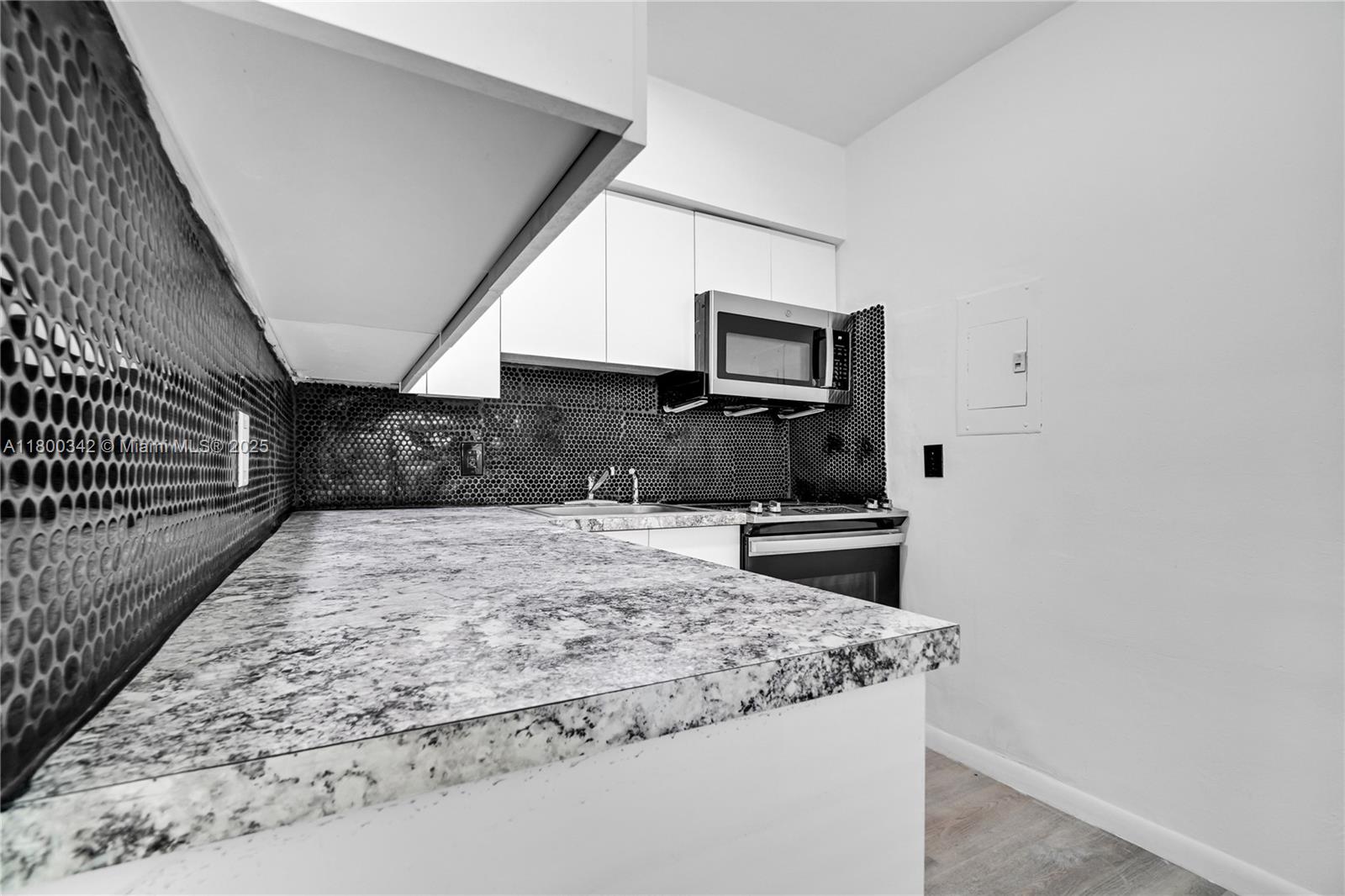 A kitchen features white cabinets, a black penny tile backsplash, and a granite countertop — 46 NW 62nd St # 4, Miami FL 33150, MIAMI, FL