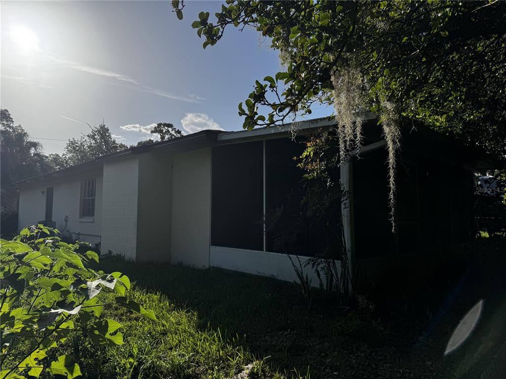 A side view of a single-story house with a screened-in porch and a grassy yard — 4051 SE 20TH COURT, OCALA, FL