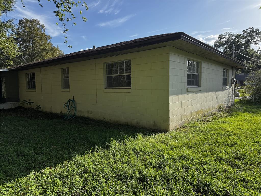 The exterior of a single-story concrete block house with a flat roof and grass yard — 4051 SE 20TH COURT, OCALA, FL