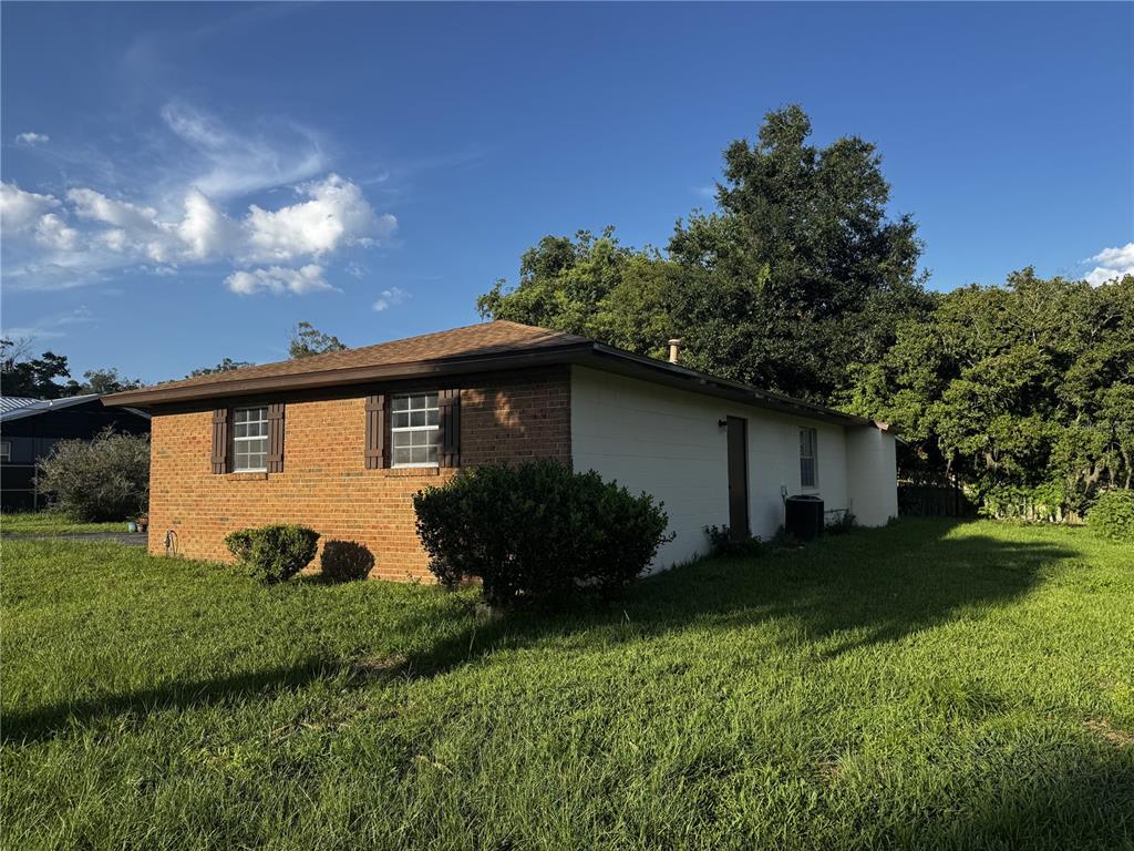 A side view of a single-story house with brick and painted block exterior walls — 4051 SE 20TH COURT, OCALA, FL
