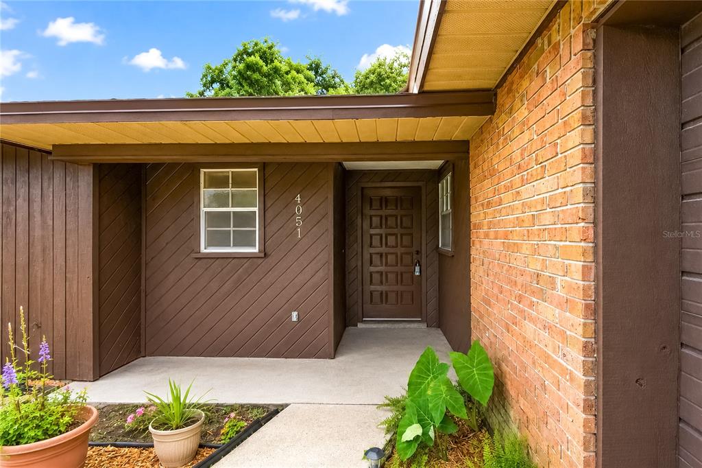 The exterior of a home features a brown door, brick siding, and a concrete walkway — 4051 SE 20TH COURT, OCALA, FL