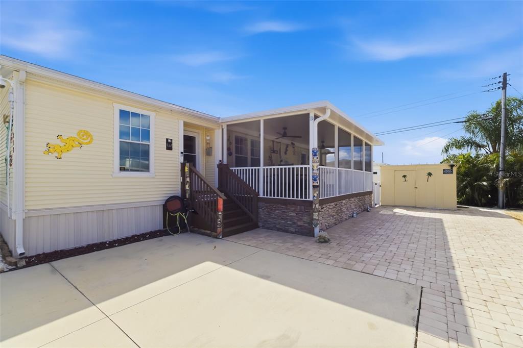 A yellow mobile home with a screened-in porch, stone skirting, and a paved driveway — 812 50TH AVENUE TERRACE W, BRADENTON, FL