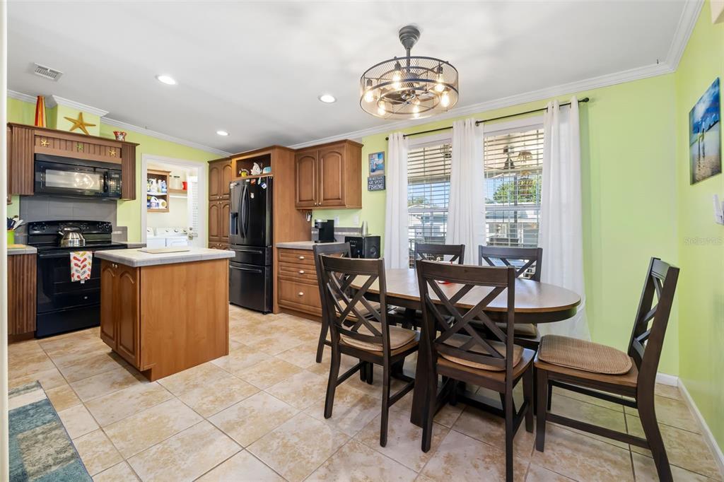 A kitchen and dining area with light green walls, wooden cabinets, and tile flooring — 812 50TH AVENUE TERRACE W, BRADENTON, FL