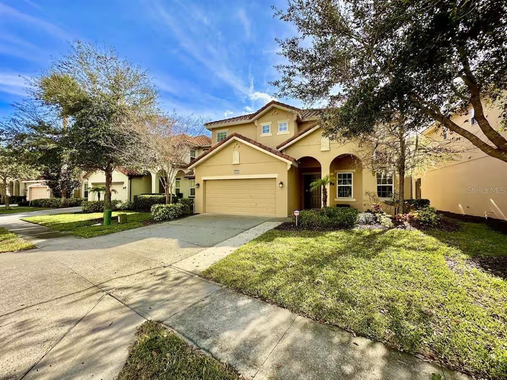 A two-story suburban house with a tan stucco exterior and a two-car garage — 4353 ACORN COURT, DAVENPORT, FL
