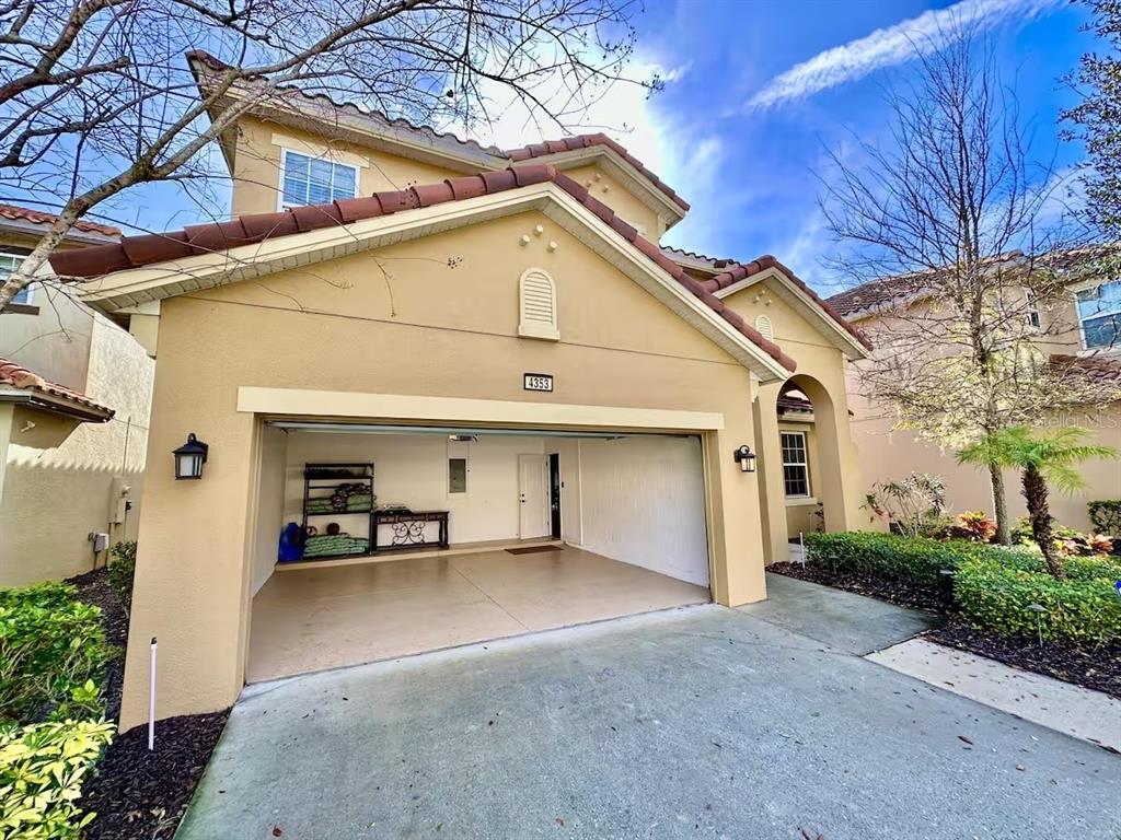 The exterior of a tan two-story house features a two-car garage and a tiled roof — 4353 ACORN COURT, DAVENPORT, FL