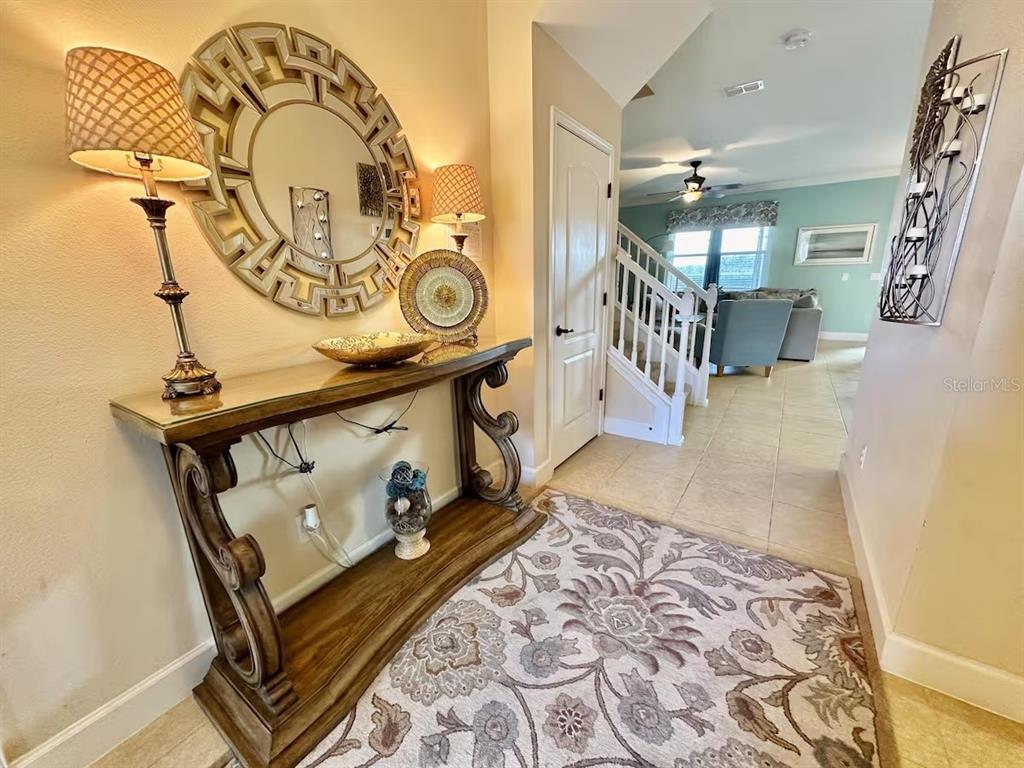 An entryway features a console table, a large circular mirror, and a patterned area rug — 4353 ACORN COURT, DAVENPORT, FL