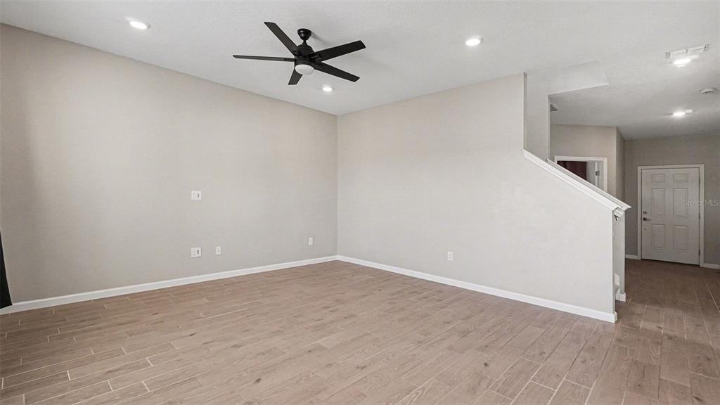 An empty living room features light-colored walls, a ceiling fan, and wood-look tile flooring — 1795 NW 44TH COURT ROAD, OCALA, FL